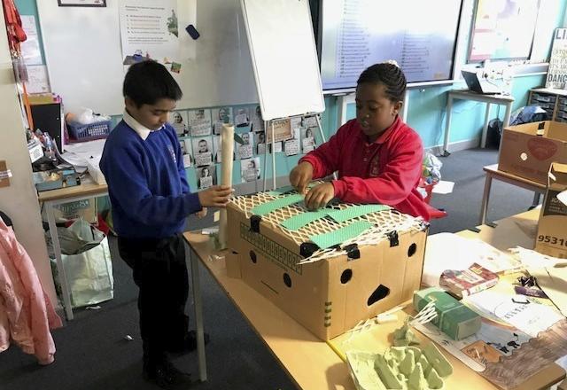 two school children interacting over craft box in classroom