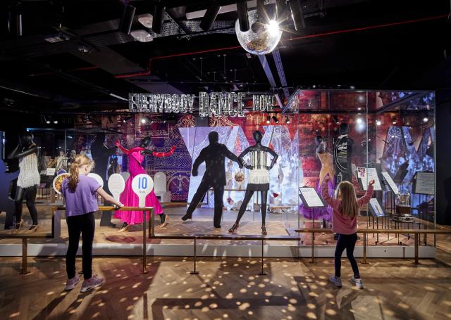 two girls dance in front of a strictly come dancing exhibit at showtown by Buttress Architects
