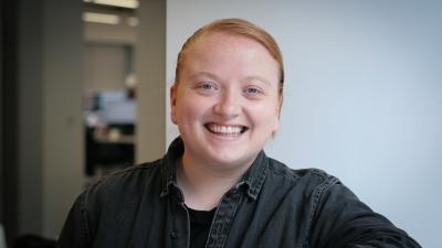 Headshot of Christina Marsh. A smiling woman wearing a black denim shirt.